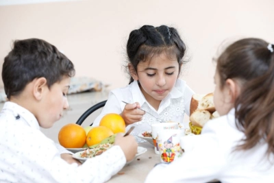 Three children enjoing their lunch.