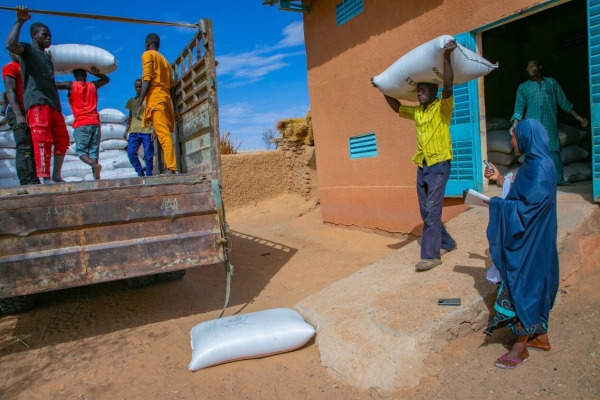 People loading bags of grain into a truck.