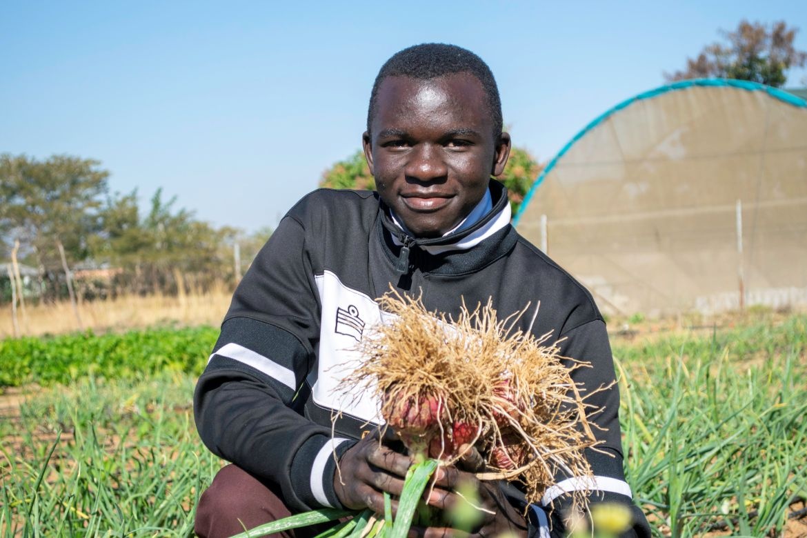 Elijah Winawanga showing the freshly harvested oninons from the St.Vincent School GArdens. Credit: World Food Programme / Joseph Kaluba