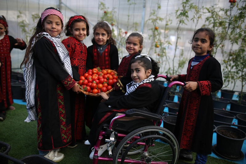 Smiling kids proudly displaying freshly picked tomatoes.