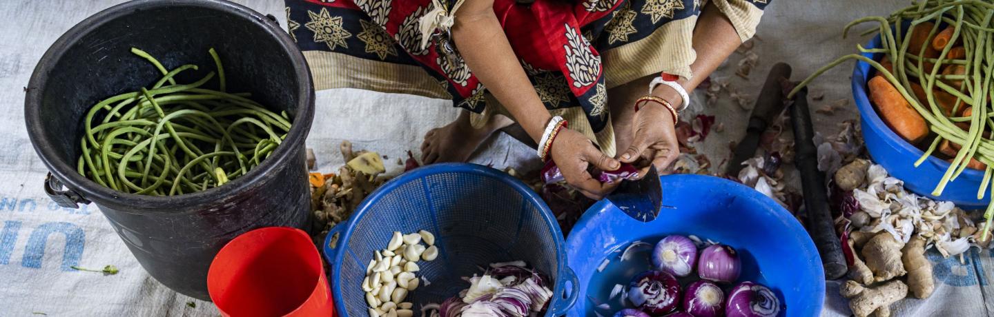 A woman cutting vegetables on a table.