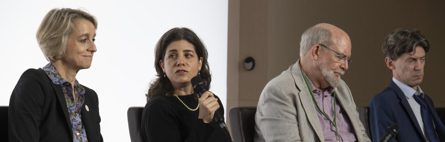 People sitting in chairs, talking in a conference. 
