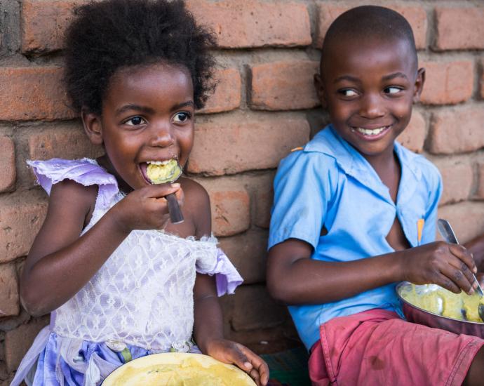 Two kids eating school meals.