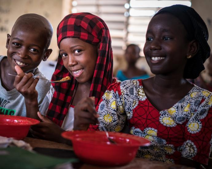 Three children eating and smiling 