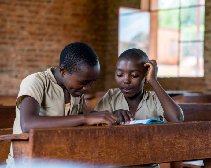 Two children, absorbed in a book, eager to learn.
