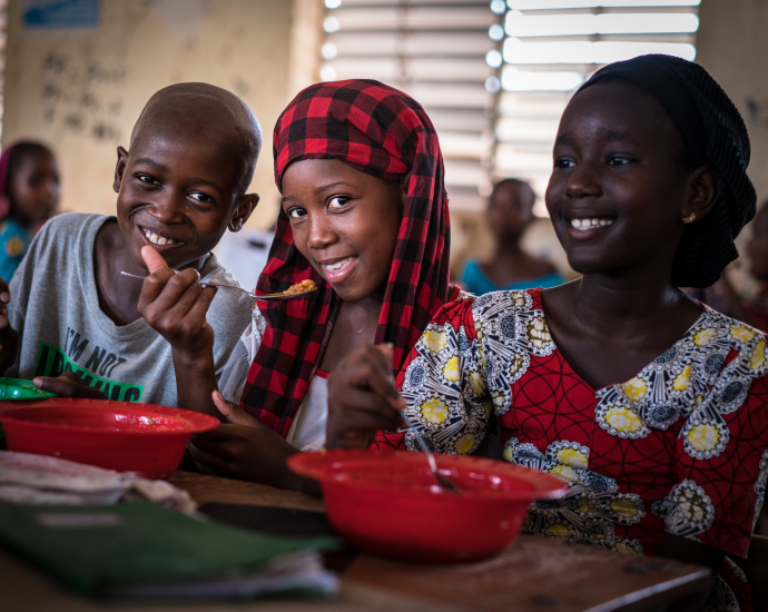 Children eating lunch together at school table.