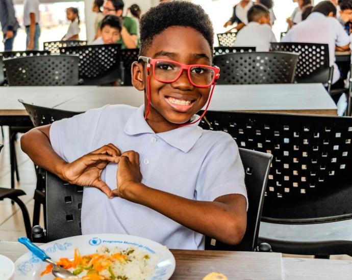 A young kid is enjoying his school meal