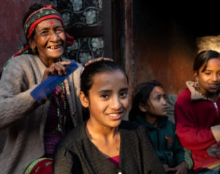 A woman carefully trims the hair of a young girl. 