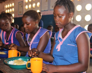 Three girls having their meals at school.
