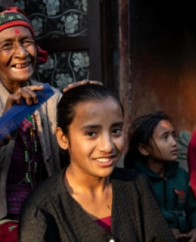 A woman carefully trims the hair of a young girl. 