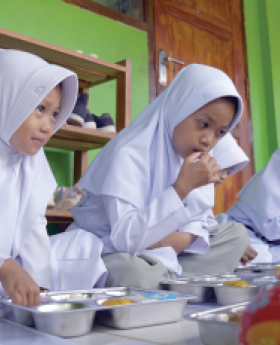  Children sitting on floor, eating together.