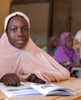 A student sits attentively at a desk in a classroom.