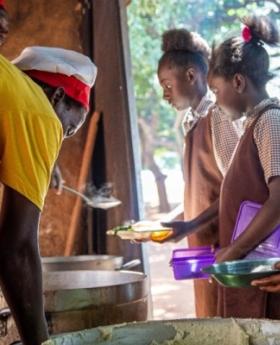A group of children in Zambia receiving food in a kitchen.