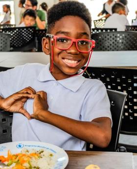 A young kid is enjoying his school meal